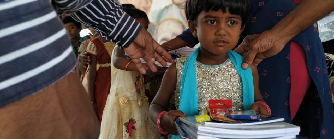 A young girl receiving school supplies at a Vidhyadaanam distribution event